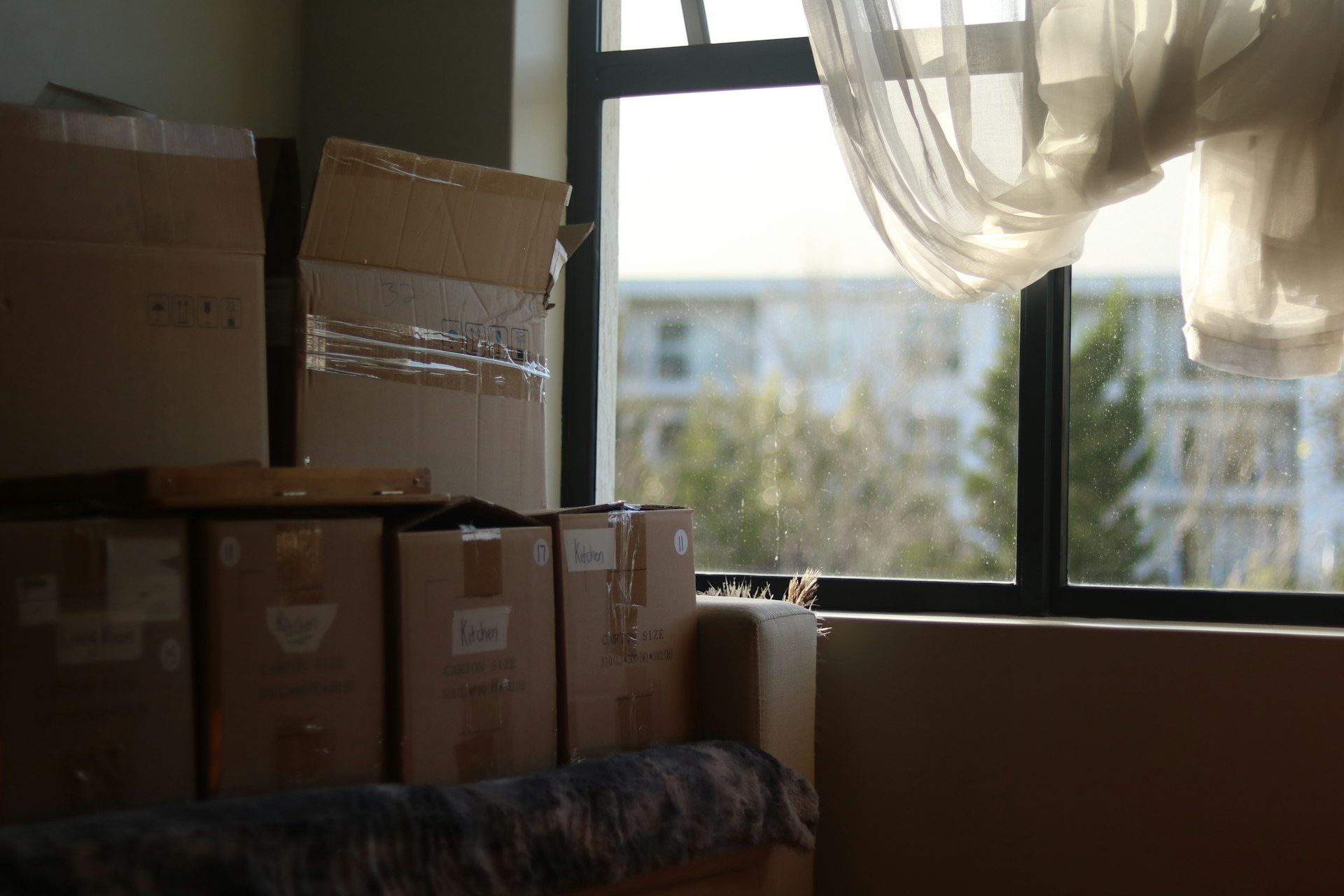 Packed moving boxes stacked by a window in a new home