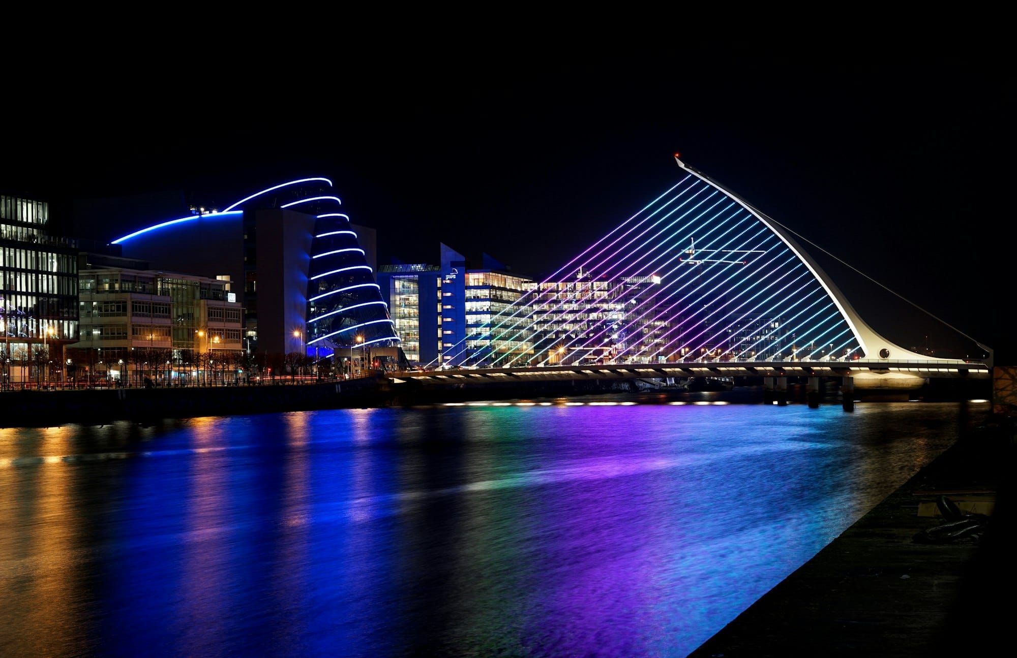 The Samuel Beckett Bridge and Dublin Docklands lit up at night over the River Liffey