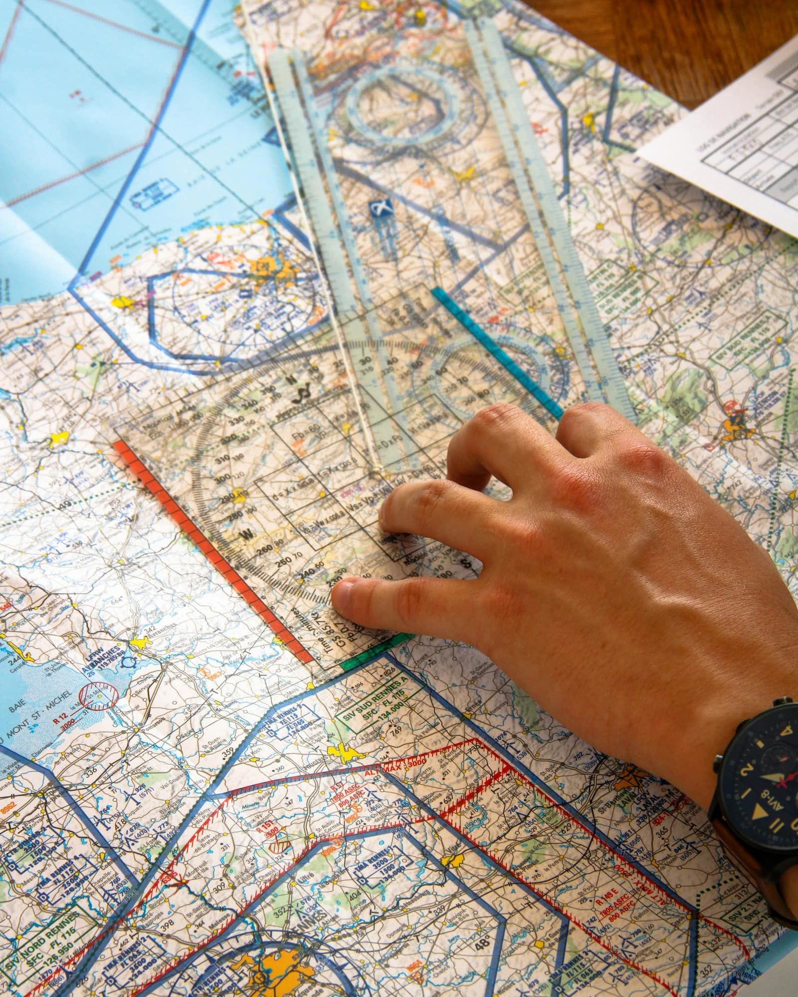 A hand planning a route with a ruler on an aviation chart