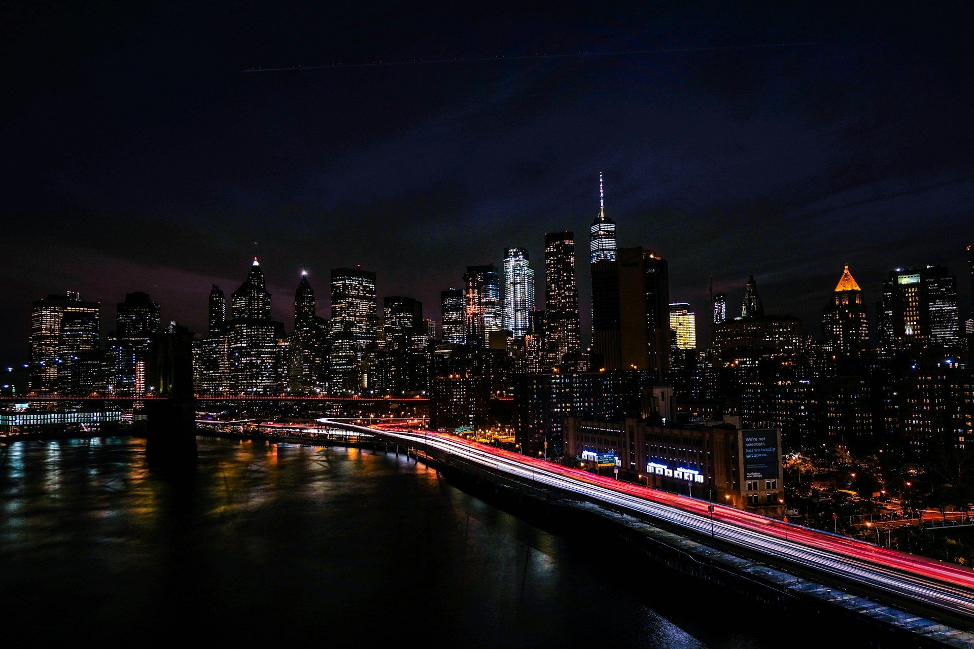 The New York City skyline at night with light trails along the riverside highway