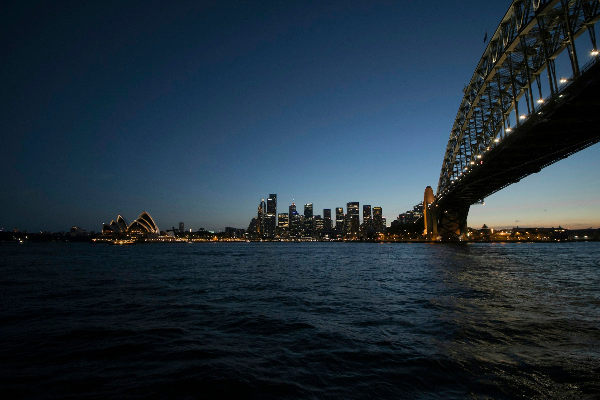 Sydney Harbour with the Opera House, the city skyline and the Harbour Bridge at dusk