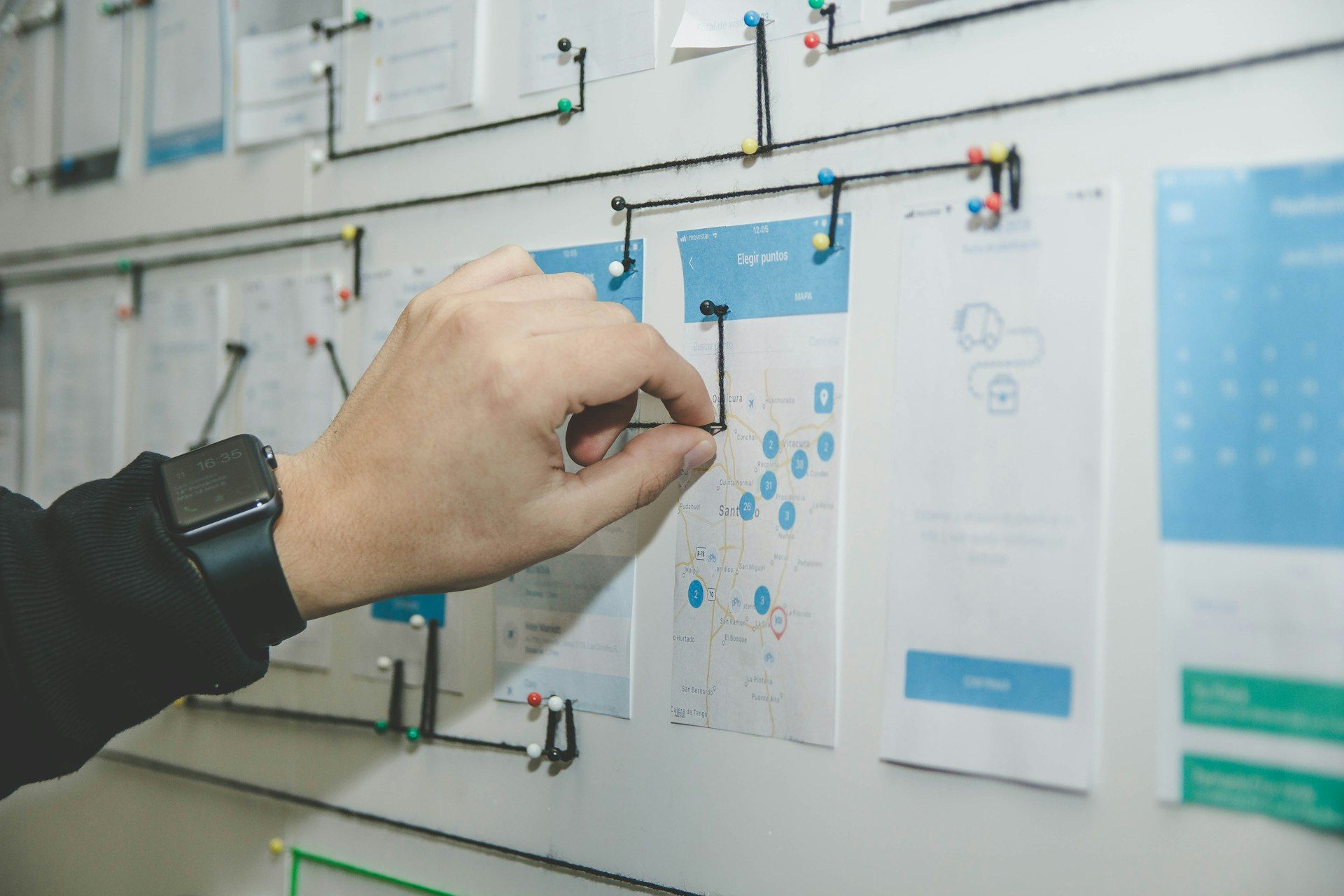 A hand pinning sketches and wireframes to a planning board